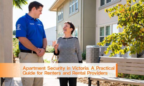 Security officer speaking with a woman in a sunlit apartment courtyard.