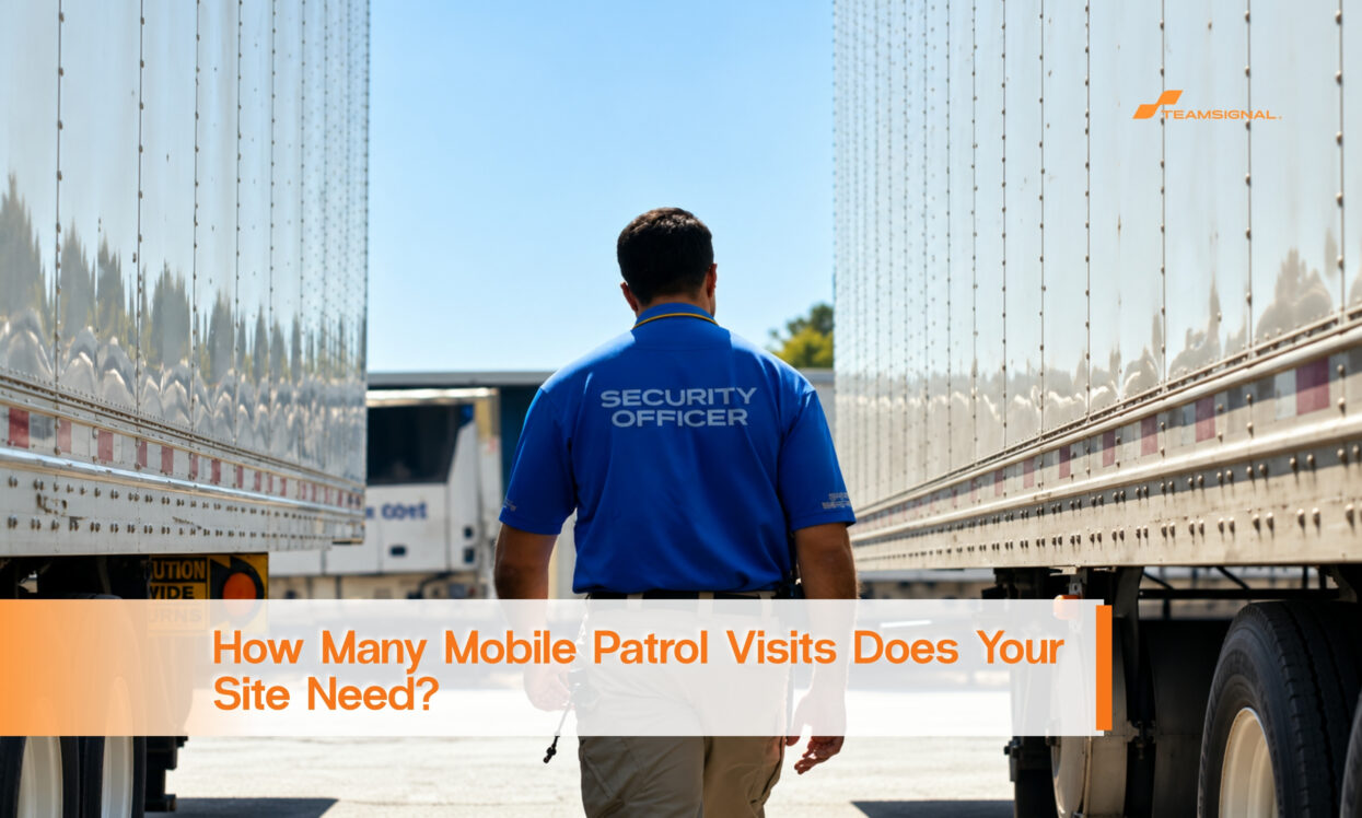 A security officer walks between two parked truck trailers at a freight yard.